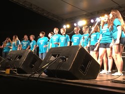 The Colonial Kids, wearing light blue shirts, sing on the Main Stage at the festival.