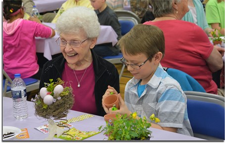 Senior citizen and student planting flowers at the luncheon.