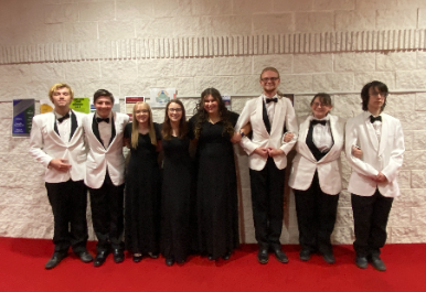 8 MVHS choir students wearing black dresses and white tuxedos.