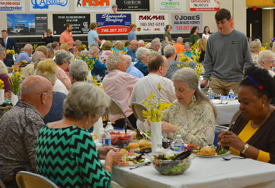 Senior citizens enjoying lunch as a National Honor Society student looks on.