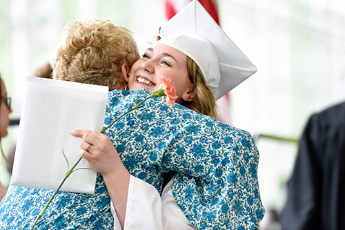 Student receiving hug during graduation.