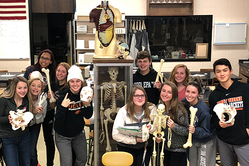 Students in physiology class holding various skeletal parts.