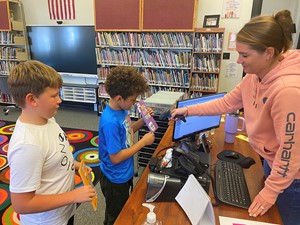 Students signing out books with a librarian.